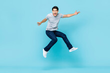 Energetic Happy Young Asian Man In Casual Clothes Jumping Studio Shot Isolated In Light Blue Background