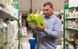 Portrait of man holding plastic gallon with liquid contents in hypermarket