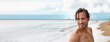 Handsome good looking man swimming at beach looking to the side on copy space banner. Male beauty model smiling portrait outdoors panoramic crop.