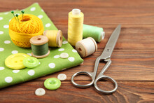 Different Sewing Accessories On The Table. Threads, Needles, Pins, Fabric And Sewing Scissors Close Up
