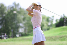 Female Golfer Smiles And Looks Along After Making Hit With Club. Women's Golf Concept