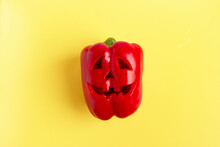 Scary Face Carved On Red Bell Pepper For Halloween On Yellow Background. 