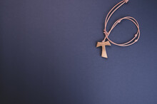 Closeup Of A Wooden Tau Cross Necklace Isolated On A Dark Background