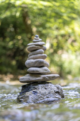 Wall Mural - Vertical shot of a pyramid of stones balanced on a river water