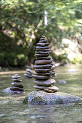 Wall Mural - Vertical shot of many stone pyramids balanced on a river water