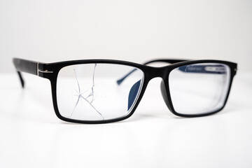 close up of broken black glasses on a white background. vision examination and repair.