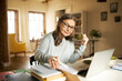 © shurkin_son - Serious confident middle aged female journalist with cup of coffee sitting at desk with books and laptop, making research, studying literature. Attractive mature woman copywriter working from home