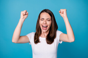 Photo of attractive pretty funny lady good mood raise fists celebrate achievement screaming loudly ecstatic competition win wear casual white t-shirt isolated blue color background