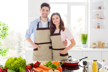 Portrait of positive friendship vegan couple spouses enjoy family hobby cooking day hug embrace ready prepare organic nutrition meal in house kitchen indoors