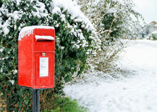 An English Red Post Box With A Dusting Of Snow In Winter