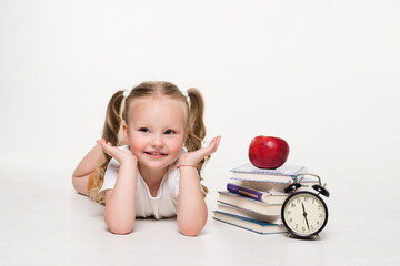 Wall Mural - Education and school concept. Smiling little student girl with book clock and apple lying on the floor