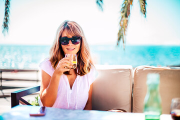 Wall Mural - Happy woman enjoying sunny day while relaxing outdoor sofa