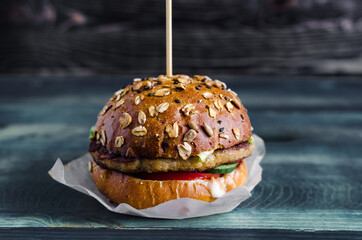 Burger with meat and vegetables on a wooden background close up fast food