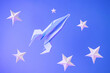 Paper origami rocket flies among paper stars on a blue background. Space concept. International Day of Human Space Flight, Cosmonautics Day.