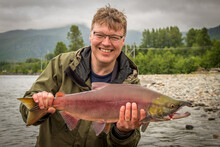 A Happy Fisherman Proudly Holding Up A Sockeye Salmon