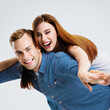 Portrait image of expressive amorous funny laughing couple. Standing piggy back ride models in love studio concept, isolated against white background. Man and woman posing together. Square composition