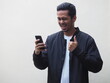 © KrishnaTedjo - An adult Asian man wearing black bomber jacket and white shirt showing happy face while looking to the mobile phone isolated on white. Space for copy.
