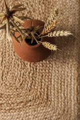 Wall Mural - Dry rye, wheat stalks in red clay pot on straw background. Minimal interior design decoration.