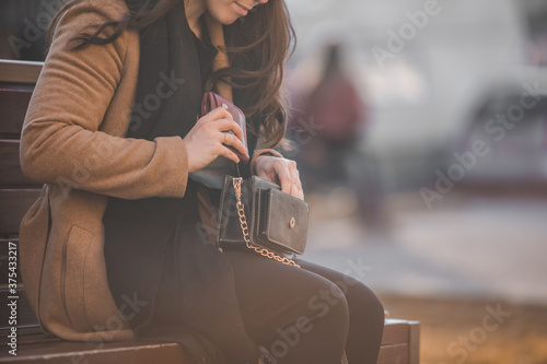 woman looking different stuff in her purse sitting on city bench Tableau sur Toile