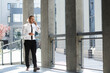 © YURII MASLAK - Portrait of a successful young businessman. A curly-haired man in a white shirt with a telephone against the background of a modern business center.