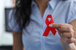 Woman holding red ribbon symbol in her hand. Prevention of breast diseases in women concept