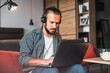 © Petryshak - Man relaxing on sofa using laptop and smartphone.	Man sitting on the sofa of a living room and working on his laptop.