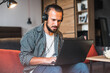 © Petryshak - A businessman is at home. He is using a laptop on the kitchen counter while listening online webinar. Young man working with laptop.