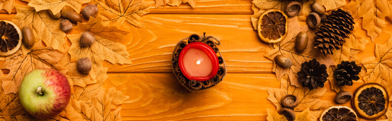 Wall Mural - top view of burning candle with autumnal decoration on wooden background
