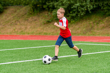 Football soccer training for kids. Boy running and kicking soccer ball. Young boy improving soccer skills