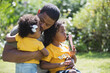 © Tom Merton/Caia Image - Affectionate father hugging daughters in sunny summer backyard