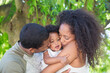 © Tom Merton/Caia Image - Affectionate parents kissing toddler daughter under tree
