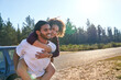 © Trevor Adeline/Caia Image - Happy affectionate couple piggybacking at sunny summer roadside