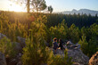 © Trevor Adeline/Caia Image - Young hiking couple relaxing on rock in sunny scenic woods