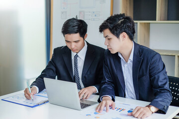 Wall Mural - Two young asian businessman talking and working together at office.