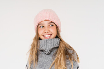 Cute smiling teenage girl in pink knitted hat and cozy gray poncho isolated on the white background