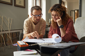 Wall Mural - two architects sitting at the table and discussing blueprint of new building at office