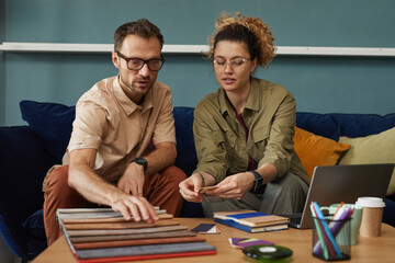 Wall Mural - two designers sitting on sofa and working with fabric samples they discussing new fashion project