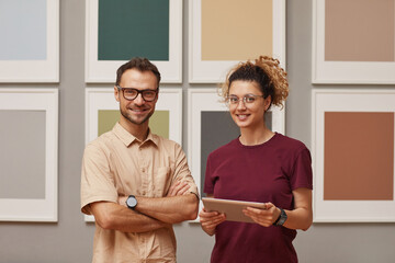 Wall Mural - portrait of two designers working on digital tablet smiling at camera while they standing at art gal