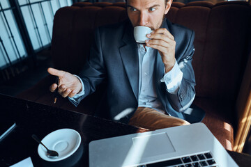 Business man sitting in a cafe in front of a laptop with a cup of coffee work technology lifestyle