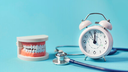 Wall Mural - White teeth model with alarm clock on blue background. me to dental health. Dentist day concept. copy space for text.