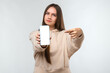 © Red Cristal - Portrait of pretty girl pointing finger at blank screen mobile phone isolated over white background