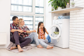 Wall Mural - family mother, father and child girl little helper in laundry room near washing machine and dirty clothes