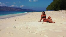 Slow Motion, Zoom In View Of A Woman In Black Bikini Sunbathing On A Pristine White Beach Of A Tropical Island.