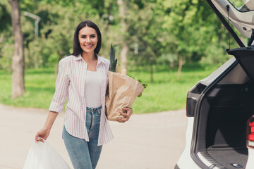 Poster - Photo of charming girl housewife go shopping mall walk parking car hold carry bags with fresh eco food vegetables in city center outdoors