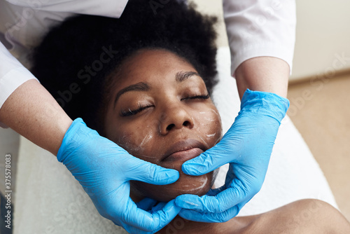 Cuadros en Lienzo A young black woman lies in the beautician's office and relaxes from gentle touches and toning massage