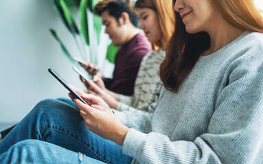 Wall Mural - Group of young people using and looking at mobile phone while sitting together