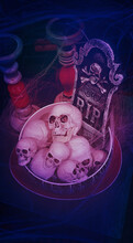 Human Skulls Stacked In Deep Round Dish,tombstone Rest In Peace With Bones Behind,surrounded By Empty Candlesticks,on Square Gray Tabletop,covered In Cobwebs In Red Black Colors.Vertical.Copy Space