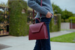 © Olha - Fashionable young woman in blue flared jeans, grey sweater, white blouse and burgundy handbag. Street style .
