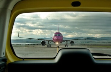 Wall Mural -  Front view of commercial passenger airliner, taxiing on airport apron after landing. View from the back window of the follow me car. Modern technology fast transportation, business travel, charters.