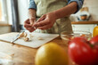 © Svitlana - Close up of hands of man in apron peeling garlic while preparing healthy meal, soup in the kitchen. Cooking at home, Italian cuisine concept